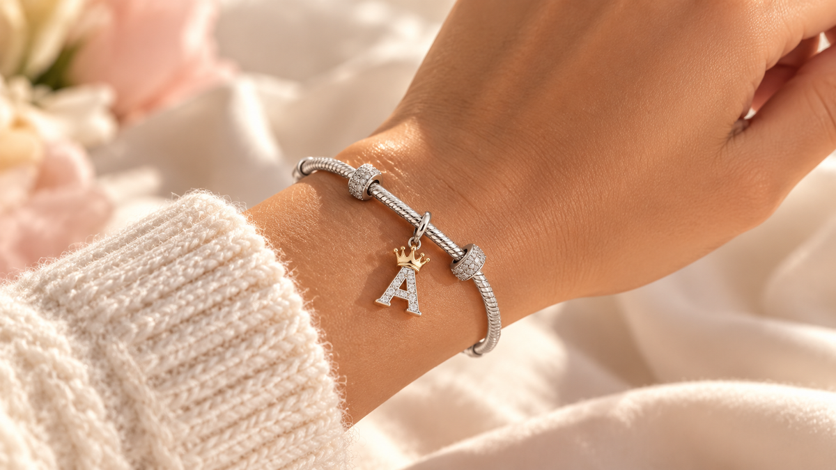 Silver bracelet with a crystal A charm topped by a gold crown on a wrist